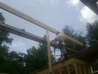 Carpenter setting a ridge beam over a new addition frame — Ice Dam Removal by Roofing Brothers in Putney