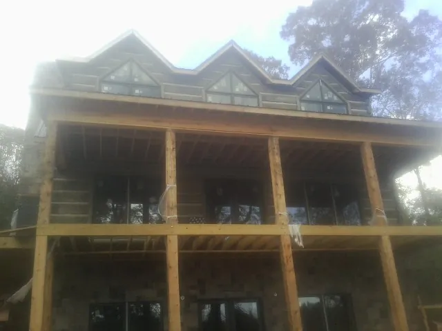 Dormers and porch framing on a large log home under construction — Roof Coating work by our crew in Putney