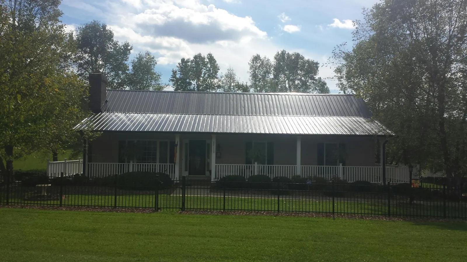 Gray metal roof on a brick ranch with a full width front porch — Gutter Guard Installation work by our crew in Putney