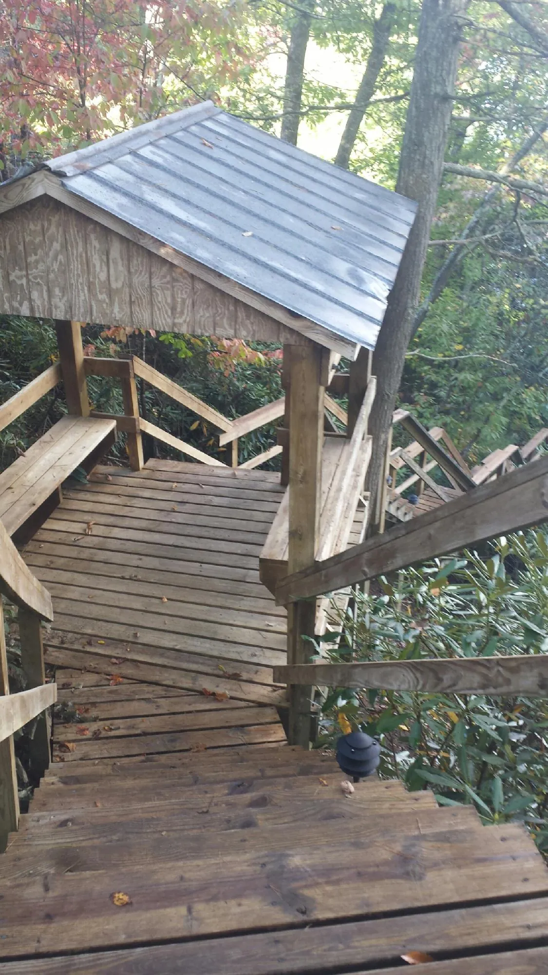 Metal roofed shelter over wooden steps on a wooded walkway — Skylight Repair & Installation work by our crew in Putney