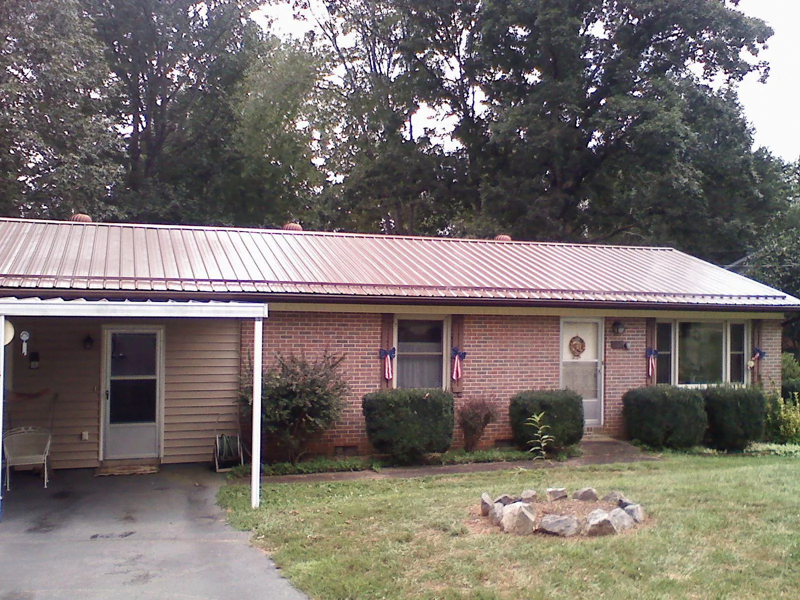 Bronze metal roof and carport on a brick ranch home — Roof Repair work by our crew in Putney